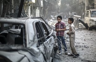 Syrian boys stand amid the destruction following an airstrike which according to local reports was conducted by forces loyal to the Syrian Government on the rebel-held area of Douma, outskirts of Damascus, Syria, 21 October 2015. 